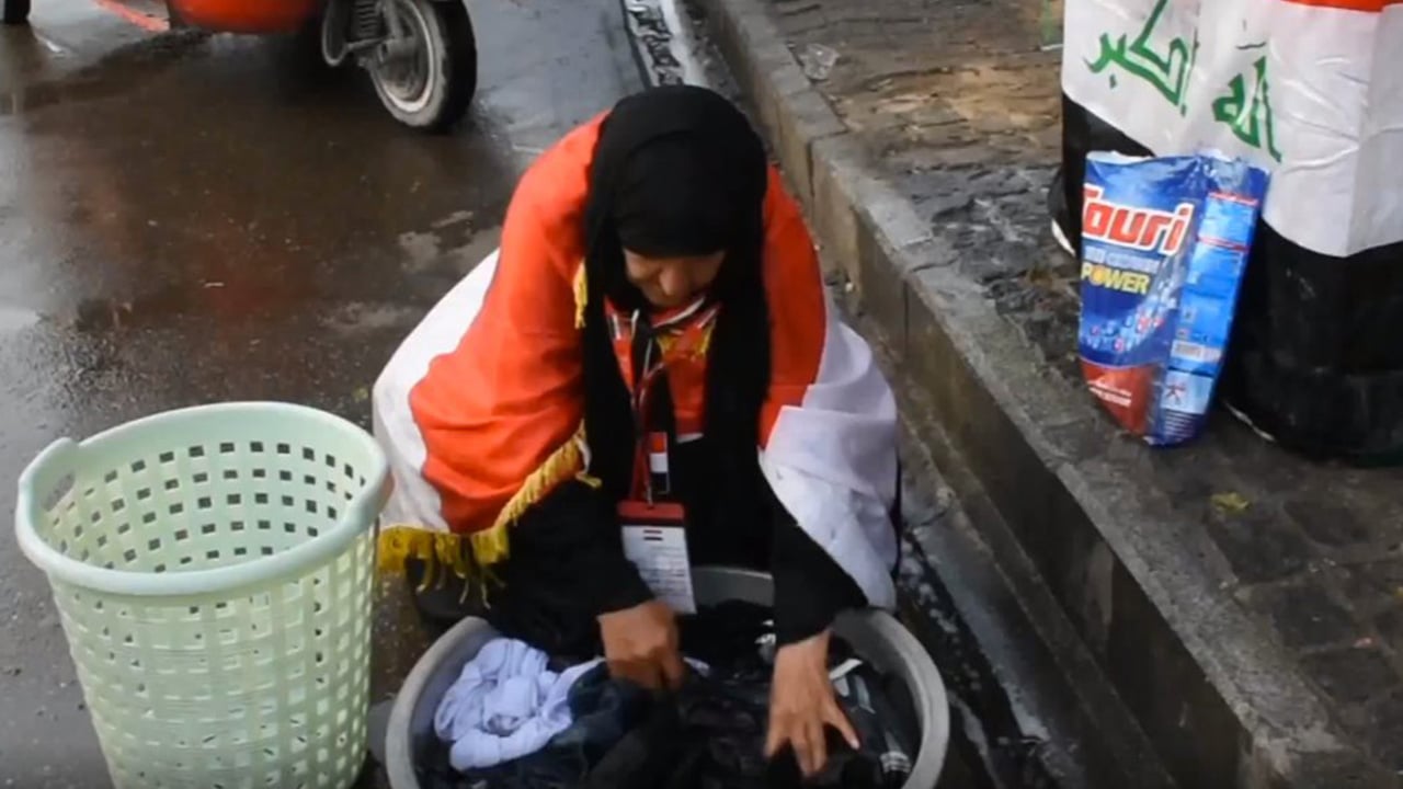 بالصور.. «غسل الملابس» يحول مسنة إلى أيقونة بساحة التحرير العراقية